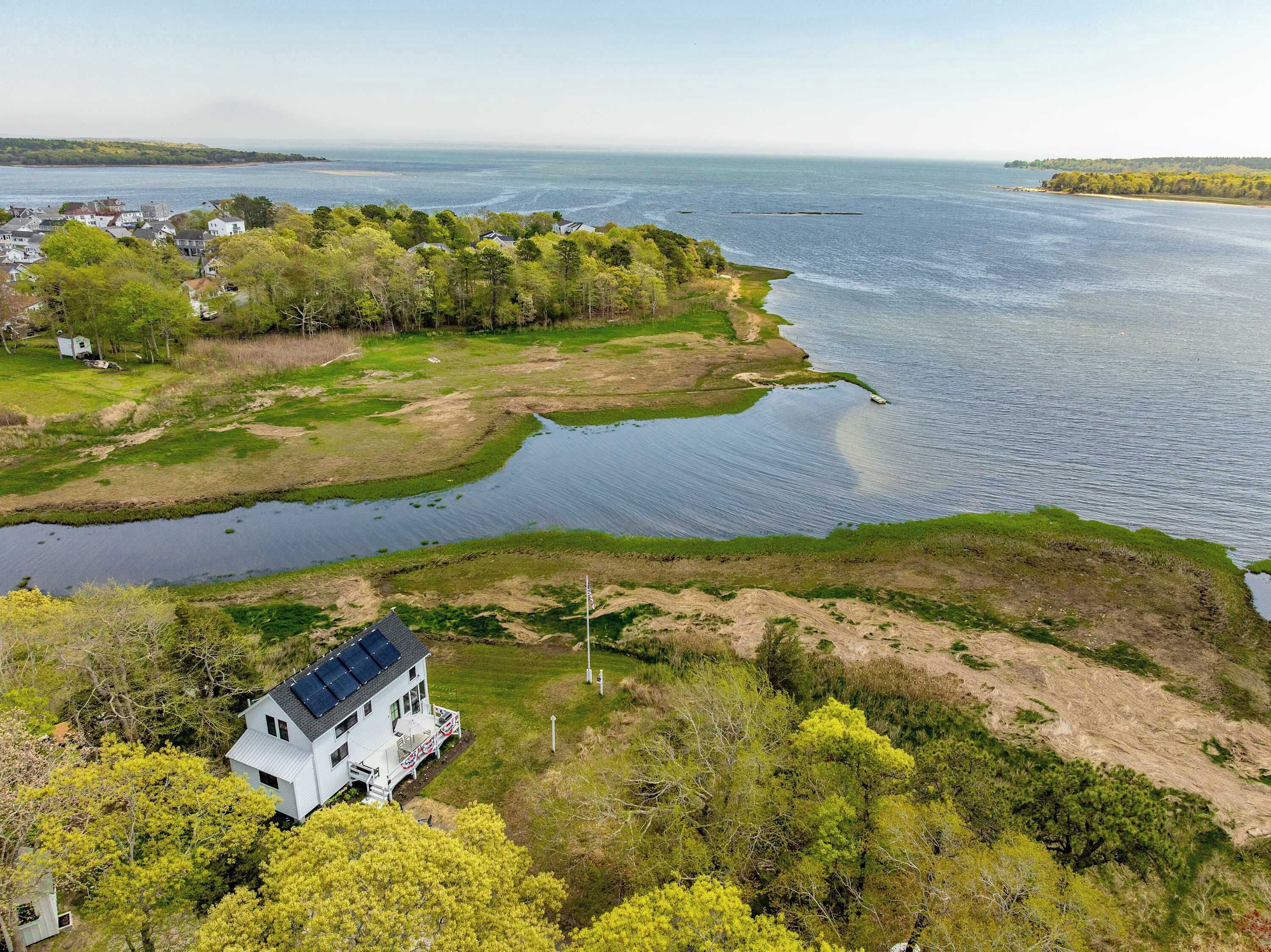 Ein Küstenanwesen mit einem Haus, einem kleinen Steg und Blick auf das Meer.