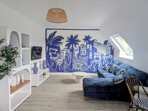 Un salón moderno con una paleta de colores azul y blanco, que incluye un sofá, una mesa de centro y un mural decorativo.