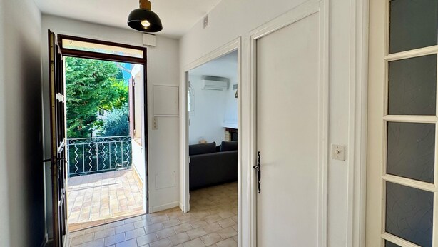 A hallway with a tiled floor, a black pendant light, a door with frosted glass panels, and a view of a balcony with a railing. - Arles apartment. Terrace overlooking garden, 2 bedrooms, 2 beds, living room, bathroom (Arles)