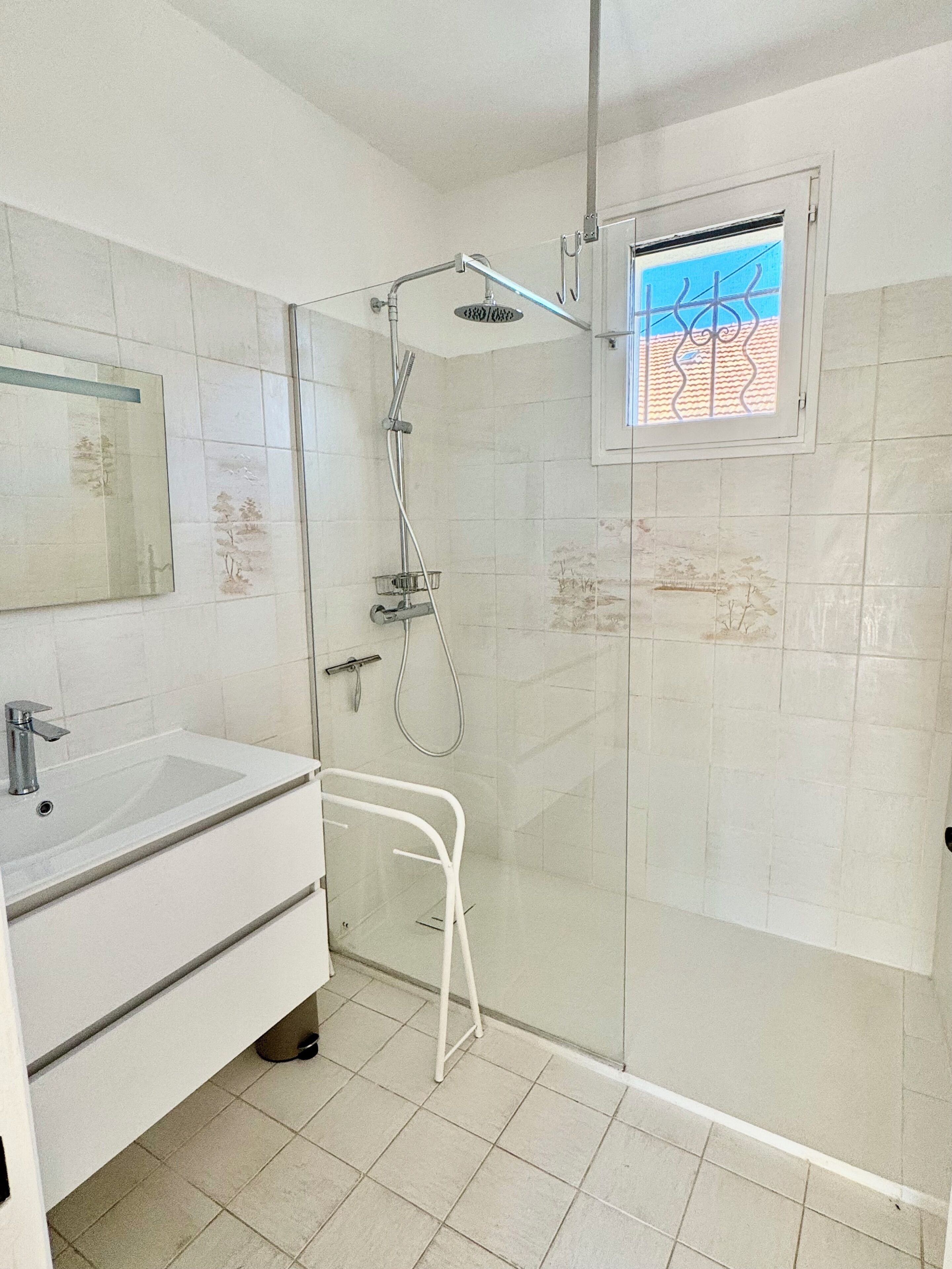 A bathroom with a shower, a sink, and a window with a view.