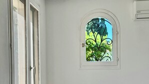 A room with a white radiator, a small white stool, a black table, and a window with a decorative iron grille. - Arles apartment. Terrace overlooking garden, 2 bedrooms, 2 beds, living room, bathroom (Arles)