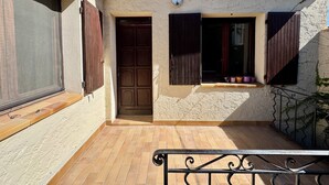 A building with a tiled patio, a door, and windows with shutters. - Arles apartment. Terrace overlooking garden, 2 bedrooms, 2 beds, living room, bathroom (Arles)