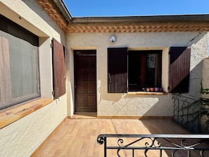 A building with a tiled patio, a door, and windows with shutters. - Arles apartment. Terrace overlooking garden, 2 bedrooms, 2 beds, living room, bathroom (Arles)