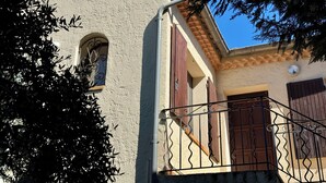 A building with a white stucco exterior, a small arched window, and a balcony with metal railings. - Arles apartment. Terrace overlooking garden, 2 bedrooms, 2 beds, living room, bathroom (Arles)