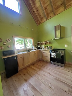 A kitchen with wooden cabinets, a stainless steel oven, a microwave, and a window with a view of trees.