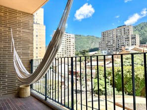 Ein Balkon mit einer Hängematte, einer Backsteinmauer und Blick auf Gebäude und Grünflächen.
