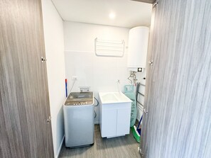 A compact bathroom with a washing machine, a sink, and a toilet. - Prime District 1302 (Bogotá)