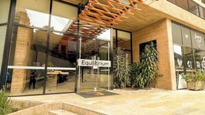 Un edificio moderno con acceso de vidrio, una escalera de madera y un letrero que dice 'Equilibrium'.