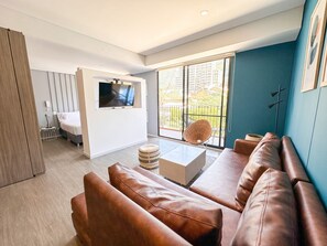 A modern living room with a sofa, a TV mounted on the wall, and a balcony with a view. - Prime District 1302 (Bogotá)