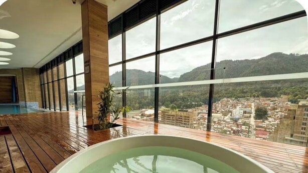 Una gran piscina interior con vistas a un paisaje urbano y montañas.