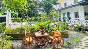 Ein Garten mit Pool, einem Holztisch mit Stühlen und einem Gebäude mit Balkon.