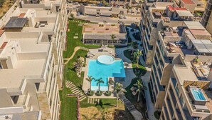 A high-rise hotel with multiple balconies, a central swimming pool, and a landscaped courtyard. - Exquisite Apartment With Balcony, TV, Wifi, Heated Pool & Gym/fitness Room (Cabo San Lucas)