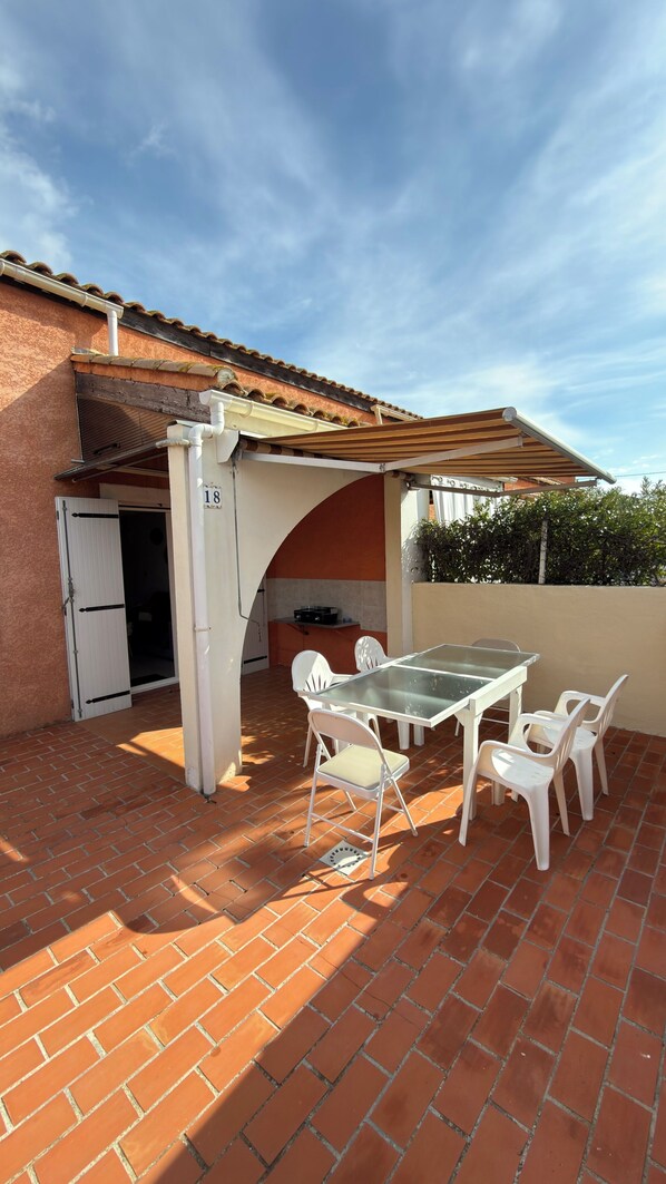 Un patio con una mesa y sillas, una pequeña cocina y una puerta con el número 18.
