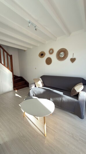 Een woonkamer met een grijze bank, een witte salontafel en decoratieve wandkunst.