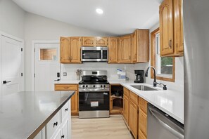 Una cocina moderna con armarios de madera, electrodomésticos de acero inoxidable y encimera blanca.