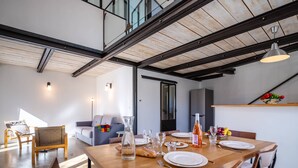 A dining area with a wooden table set for four, a sofa, and a chair in the background. - House in Villars, in the ochre hills of the Luberon, Vaucluse (Villars)