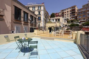 Eine Dachterrasse mit Tisch und Stühlen, einem kleinen Pool und Blick auf umliegende Gebäude.