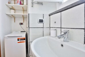 Ein Badezimmer mit einem weißen Waschbecken, einer Toilette und einer Waschmaschine.