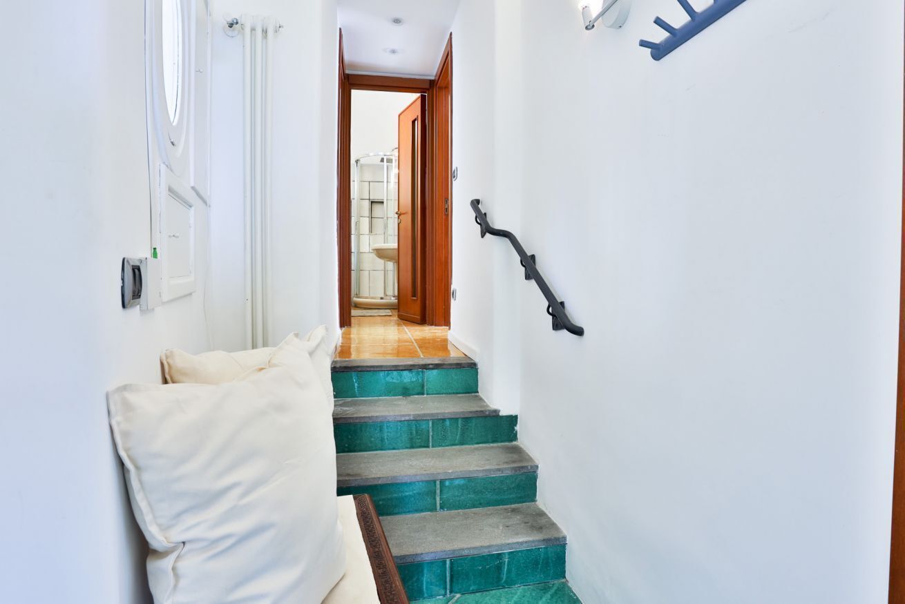 Ein schmaler Flur mit einer Treppe zu einem Badezimmer.