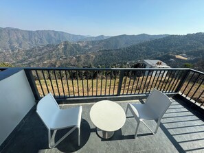 A balcony with two white chairs and a small round table, overlooking a mountainous landscape. - Ivaan Belle-Vue (Dhari)