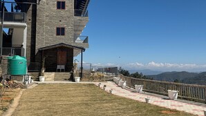 Un edificio in pietra a più piani con un balcone, una cisterna e vista sulle montagne.