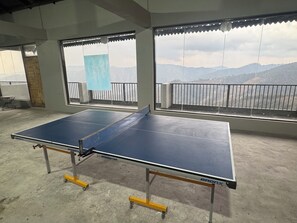 Ein Tischtennistisch in einem Raum mit großen Fenstern mit Blick auf eine gebirgige Landschaft.