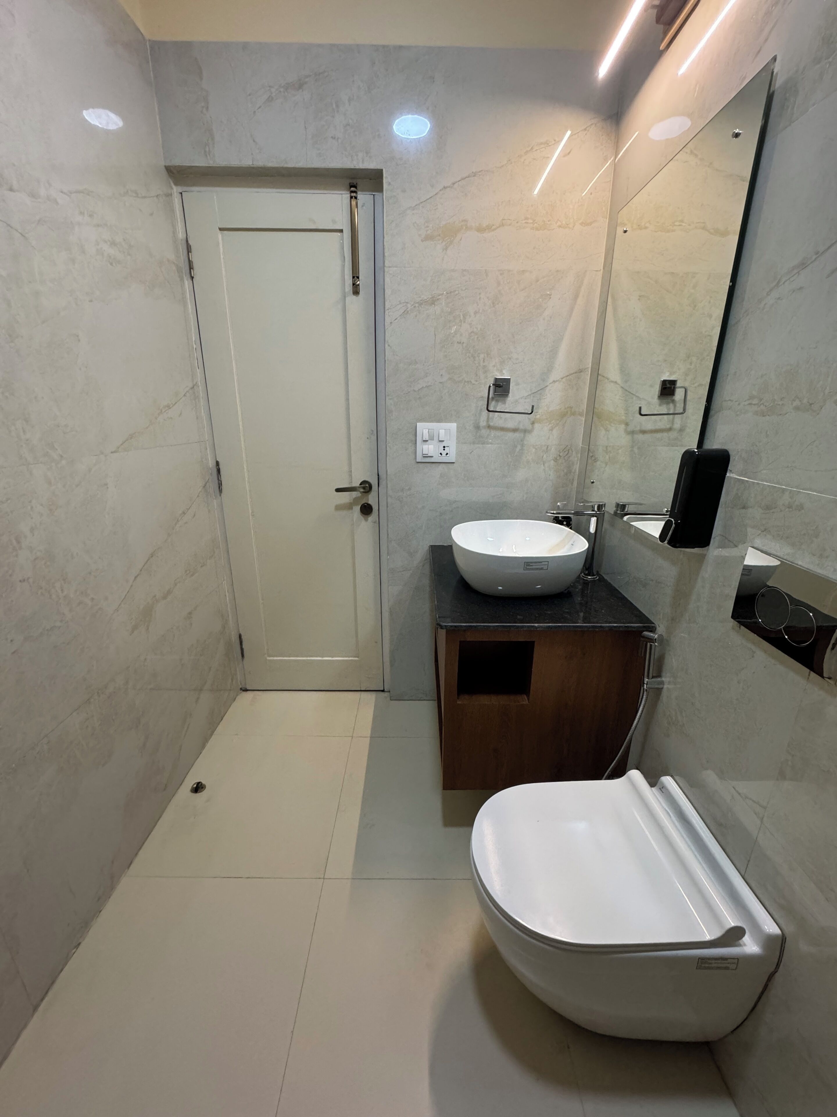 Ein Badezimmer mit Toilette, Waschbecken, Spiegel und einer Tür.