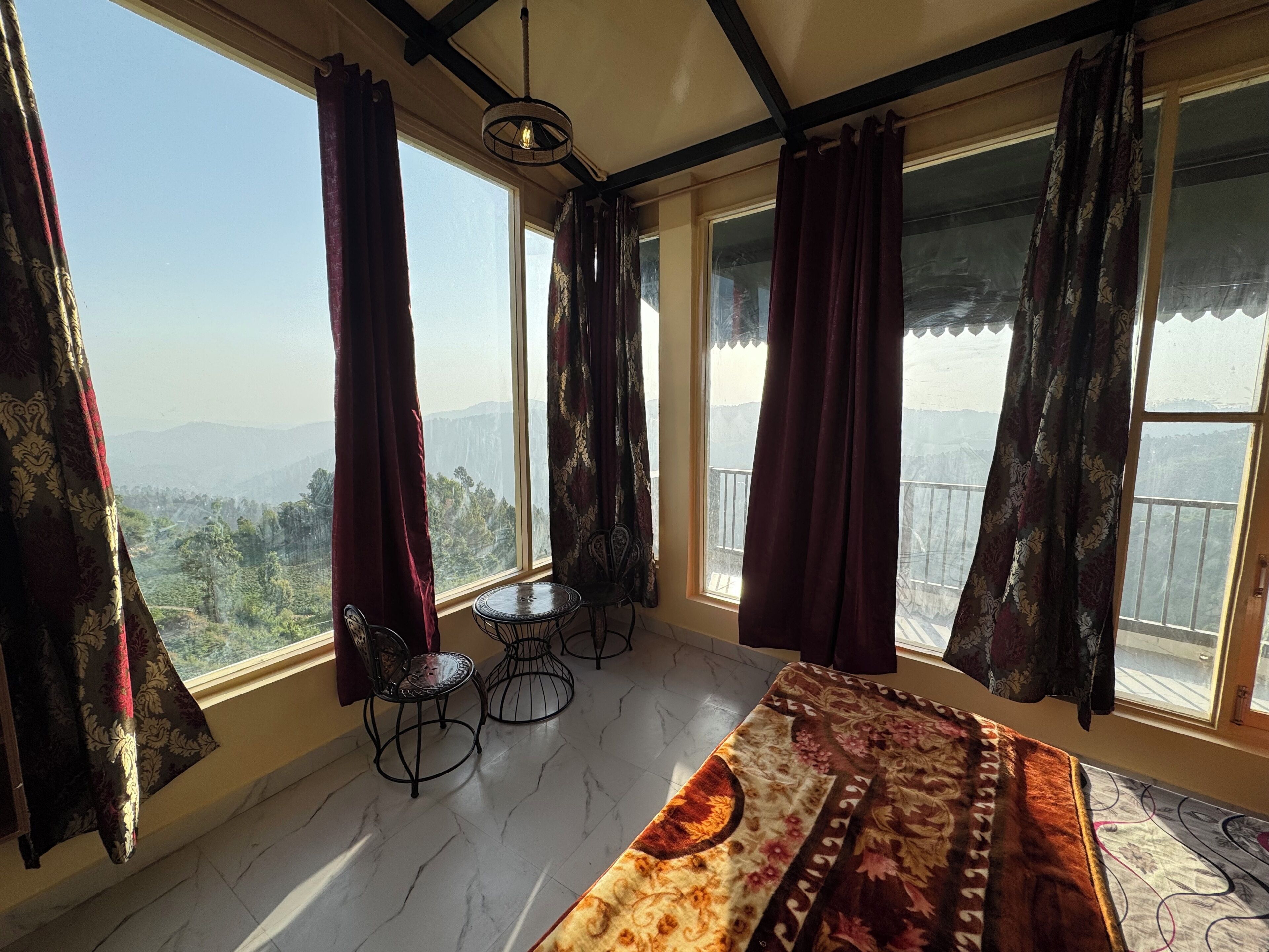 A room with a large window, a bed, a small table, and two chairs.