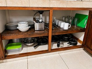 Een keuken met houten planken, een groen snijplank en divers keukengerei.