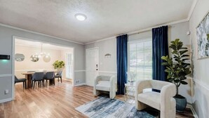 Een moderne woonkamer met een eethoek, houten vloeren en een grote potplant.