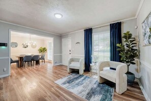 Ein modernes Wohnzimmer mit Essbereich, Holzboden und einer großen Küstpflanze.