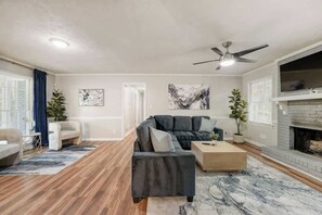 Ein modernes Wohnzimmer mit einem Ecksofa, einem Couchtisch, einem Kamin und einem Deckenventilator.