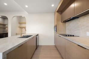 Een moderne keuken met een centraal eiland, een ingebouwde oven en roestvrijstalen apparatuur.