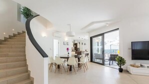 A modern interior with a curved staircase, a dining area with chairs, a flat-screen TV, and a large window. - Villa Blue Diamond (Biograd)
