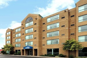 Een hotel met meerdere verdiepingen, een gevel van baksteen, grote ramen en een opvallende ingang met een blauw luifel.