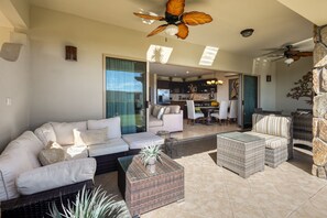 A spacious living area with a white sofa, wicker furniture, and a glass coffee table. - Stylish Condo With Pool, Ocean Views, Fitness & Private Patio Grill (Cabo San Lucas)