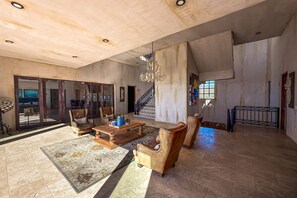 A spacious living room with a large wooden coffee table, leather armchairs, and a patterned rug. - Stylish Condo With Pool, Ocean Views, Fitness & Private Patio Grill (Cabo San Lucas)