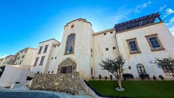 A hotel with a stone facade, multiple windows, and a green lawn area.