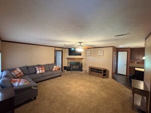 A living room with a fireplace, a sofa, and a ceiling fan. - 3-bedroom farmhouse in wonderful Mannford with AC comfort Near Keystone Lake (Mannford)