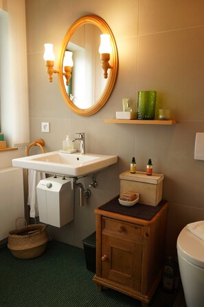 Ein Badezimmer mit Waschbecken, Spiegel, Ablage für Toilettenartikel und einem Holzschrank.