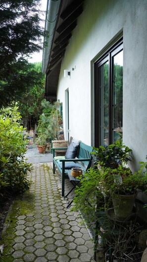 A covered patio with a bench, potted plants, and a view of the surrounding greenery. - Vacation apartment with flair and terrace with a view of the flower and herb garden (Hetzerath)