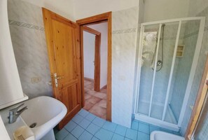 Une salle de bain avec un lavabo, une douche et une porte en bois.