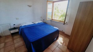 Une chambre à coucher avec un lit, une table de chevet, une fenêtre et une armoire.
