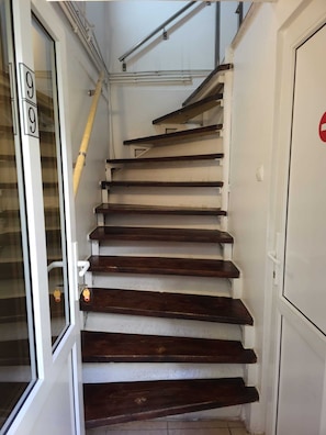 Un escalier avec des marches en bois et une porte en verre sur la gauche.