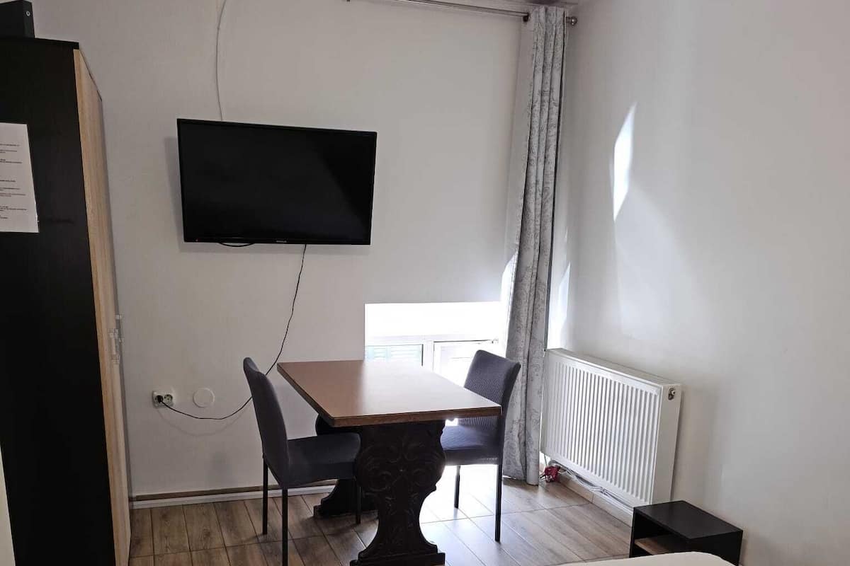 Une chambre d’hôtel comprenant un lit, un bureau avec une chaise, un téléviseur fixé au mur et une fenêtre avec des rideaux.