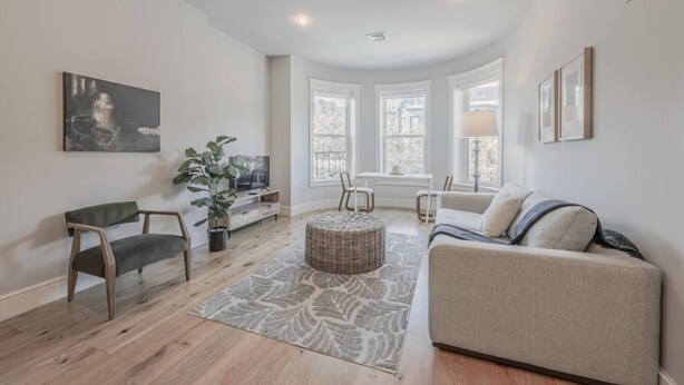 A living room with a sofa, chairs, a TV, a plant, and a window. - Spacious 1bed/1bath in Back Bay (Boston)