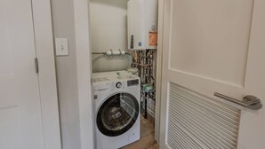 A laundry room with a washing machine, dryer, and visible plumbing. - Spacious 1bed/1bath in Back Bay (Boston)