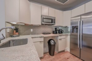 Una cocina moderna con un refrigerador de acero inoxidable, un microondas y una cafetera.