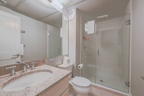 Un baño con lavamanos, inodoro y cabina de ducha de vidrio.