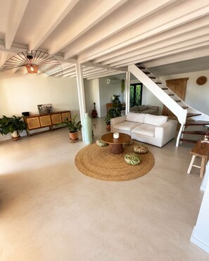 Ein geräumiges Wohnzimmer mit einem weißen Sofa, einem runden Couchtisch und einer Treppe, die zu einer weiteren Ebene führt.